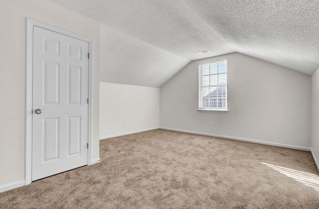 additional living space featuring carpet, lofted ceiling, and a textured ceiling