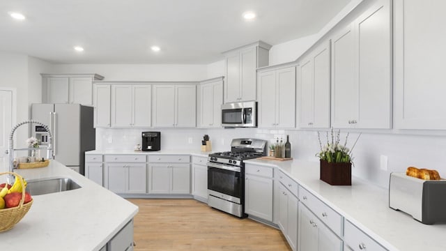 kitchen featuring decorative backsplash, sink, stainless steel appliances, and light wood-type flooring