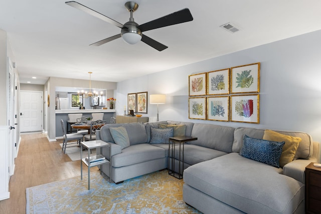 living room with ceiling fan with notable chandelier and light wood-type flooring