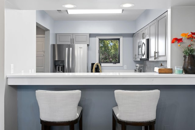 kitchen featuring appliances with stainless steel finishes, sink, a kitchen bar, and gray cabinetry