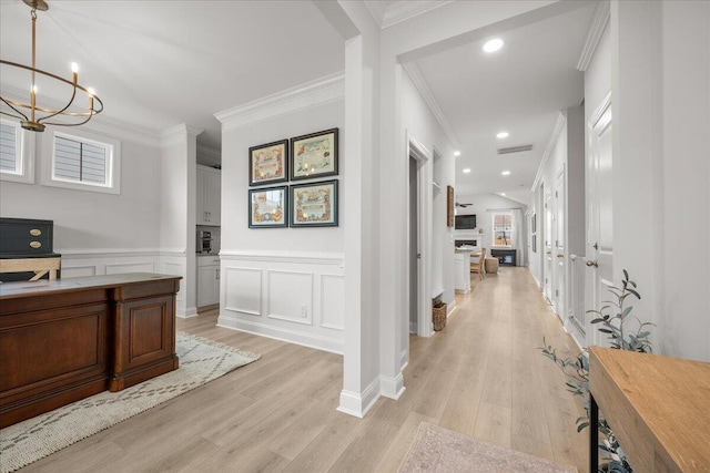 office space with light wood-type flooring, crown molding, and wainscoting