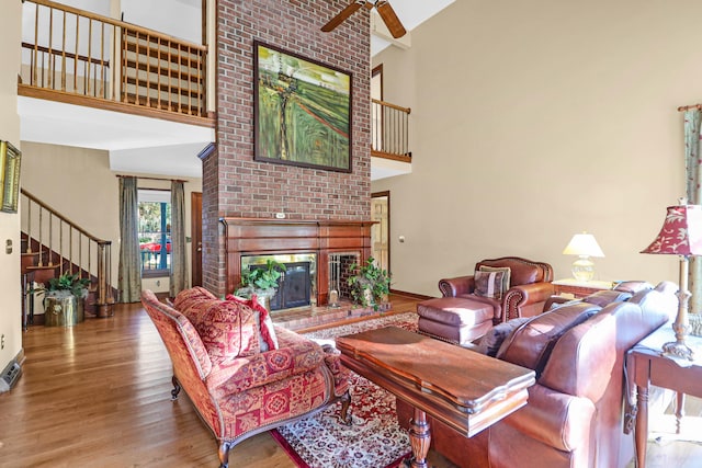 living room featuring beam ceiling, ceiling fan, high vaulted ceiling, light hardwood / wood-style flooring, and a fireplace