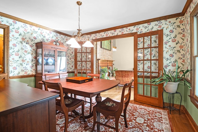 dining space with a wealth of natural light, ornamental molding, a notable chandelier, and wood-type flooring