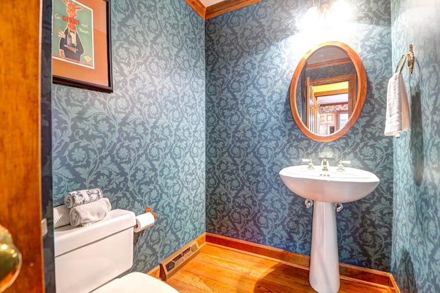 bathroom featuring toilet, ornamental molding, and wood-type flooring