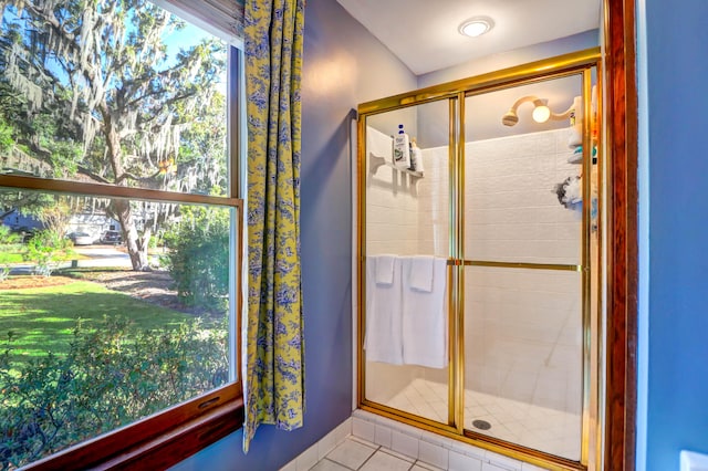 bathroom with a shower with door, a healthy amount of sunlight, and tile patterned flooring