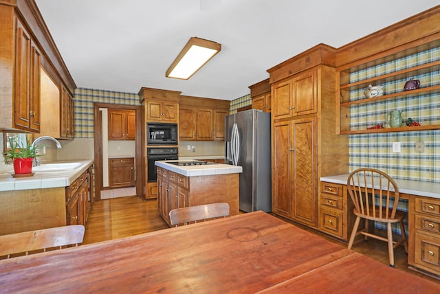 kitchen featuring decorative backsplash, hardwood / wood-style floors, built in desk, black appliances, and sink