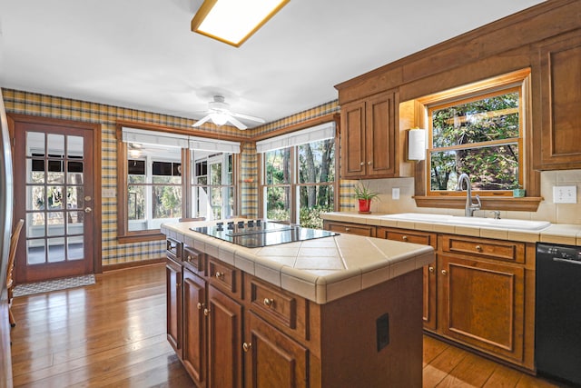 kitchen with sink, black appliances, a center island, and tile counters