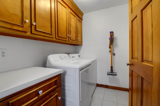 washroom featuring cabinets, washing machine and dryer, and light tile patterned floors