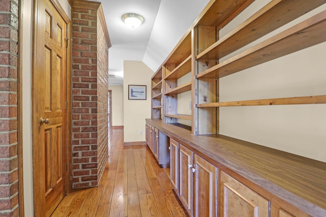 hall with lofted ceiling and light wood-type flooring