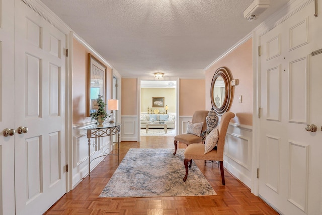 living area with crown molding, a textured ceiling, and light parquet floors