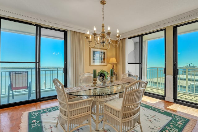 dining room featuring a water view, a notable chandelier, a healthy amount of sunlight, and parquet flooring