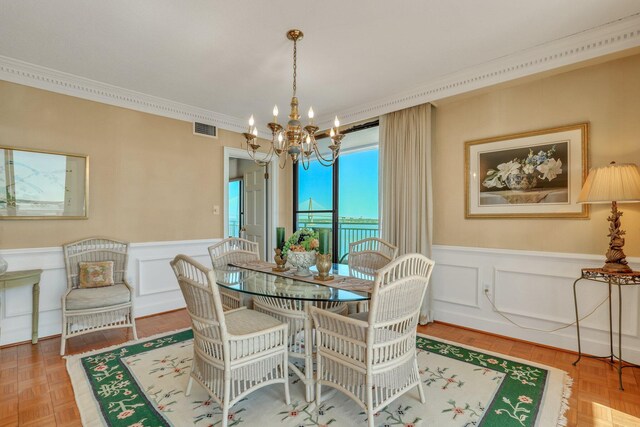 dining room with parquet floors, ornamental molding, and an inviting chandelier