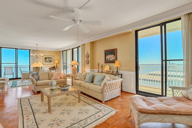 living room with ornamental molding, light parquet flooring, ceiling fan with notable chandelier, and a water view