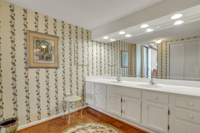 bathroom with vanity, parquet floors, and a textured ceiling