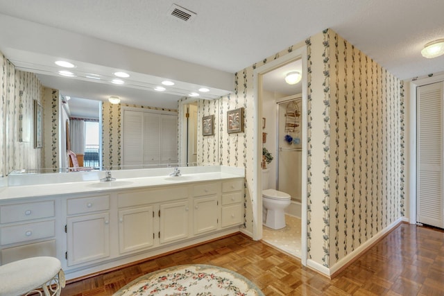 bathroom featuring toilet, parquet floors, vanity, and a textured ceiling