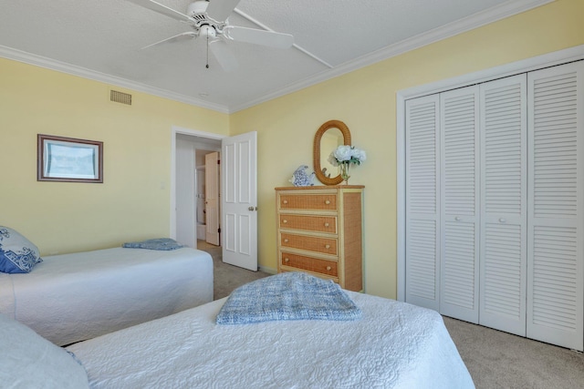 carpeted bedroom featuring a closet, ceiling fan, ornamental molding, and a textured ceiling