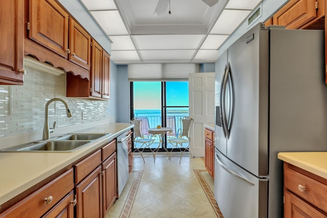 kitchen featuring stainless steel appliances, ornamental molding, sink, a water view, and tasteful backsplash