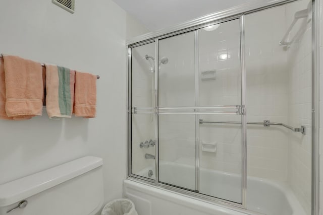 bathroom with combined bath / shower with glass door and toilet