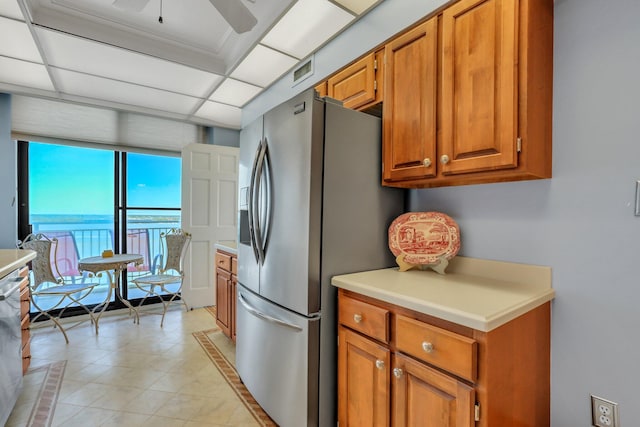 kitchen with a drop ceiling, stainless steel refrigerator with ice dispenser, a water view, and ceiling fan