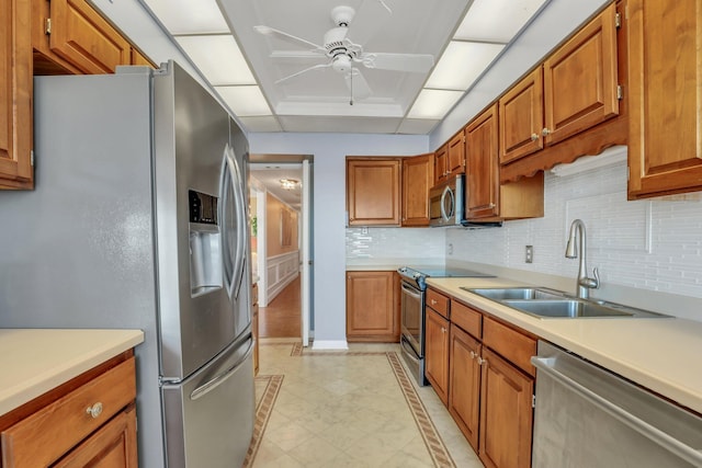 kitchen with appliances with stainless steel finishes, tasteful backsplash, sink, and ceiling fan