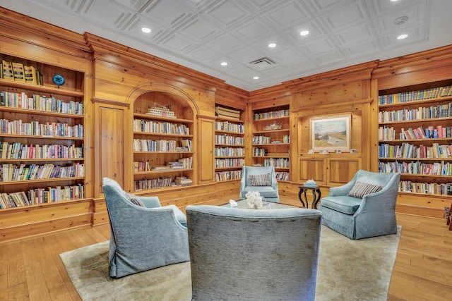 living area with wood walls, built in features, and light wood-type flooring