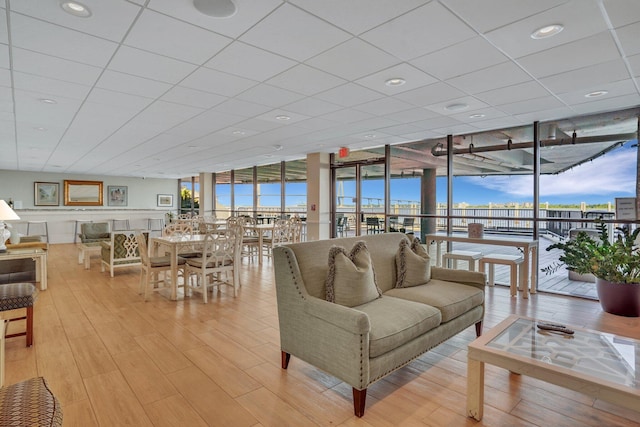 living room featuring a drop ceiling, light wood-type flooring, and floor to ceiling windows