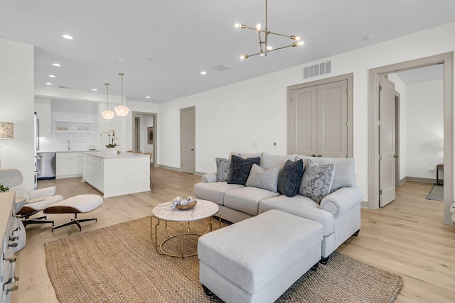 living room featuring an inviting chandelier and light hardwood / wood-style flooring