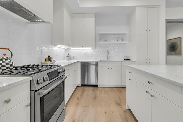 kitchen with light stone countertops, white cabinets, custom exhaust hood, stainless steel appliances, and sink