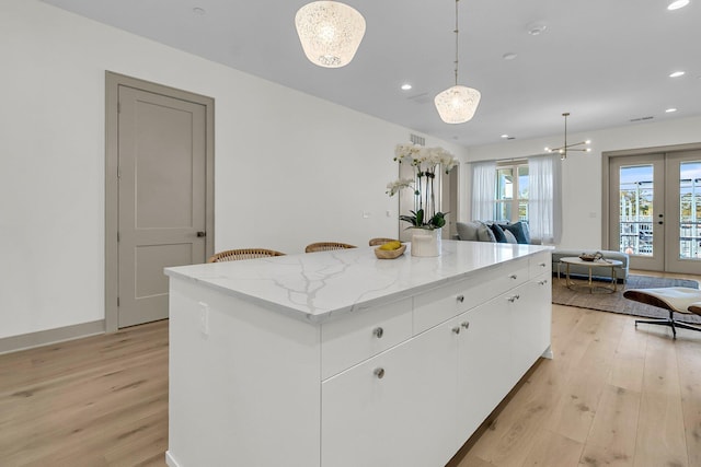 kitchen featuring white cabinetry, french doors, hanging light fixtures, a kitchen island, and light hardwood / wood-style flooring