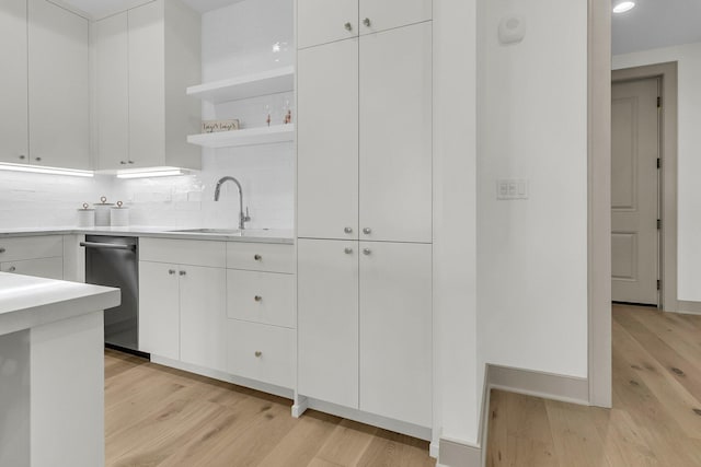 kitchen with light hardwood / wood-style floors, sink, white cabinetry, and tasteful backsplash