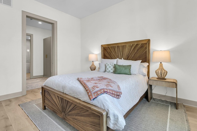 bedroom with light wood-type flooring and ensuite bath