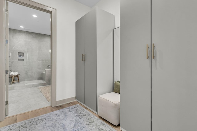 bathroom with a tile shower and hardwood / wood-style floors