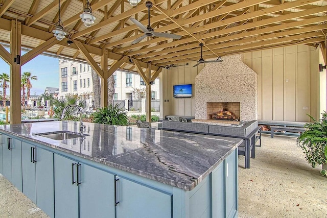 view of patio / terrace with ceiling fan, a fireplace, and sink