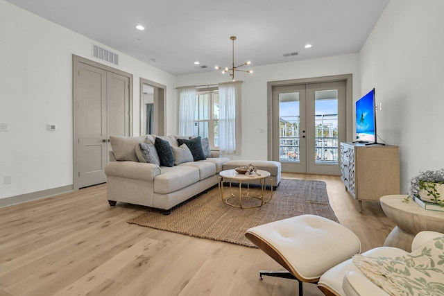 living room with french doors, an inviting chandelier, and light hardwood / wood-style floors