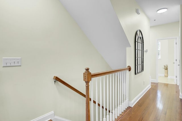 corridor featuring hardwood / wood-style floors, an upstairs landing, and baseboards