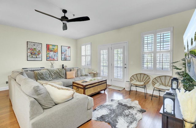 living room with wood finished floors, a ceiling fan, and baseboards