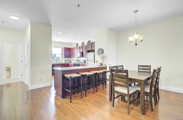 dining space with baseboards, light wood finished floors, and an inviting chandelier