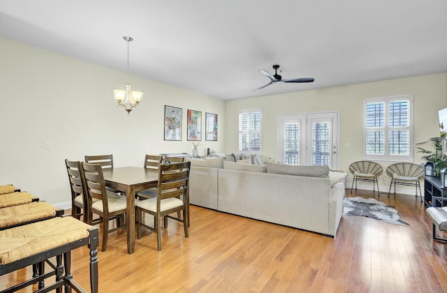 dining area with ceiling fan with notable chandelier, light wood finished floors, and baseboards