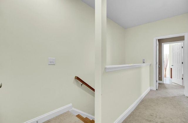 corridor featuring carpet floors, baseboards, and an upstairs landing