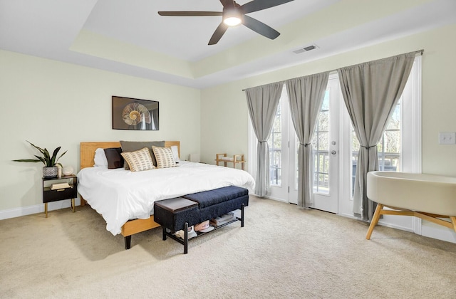 bedroom featuring visible vents, baseboards, carpet, access to outside, and a tray ceiling