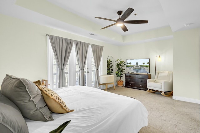 bedroom with carpet flooring, a ceiling fan, visible vents, baseboards, and a tray ceiling