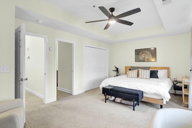 bedroom with light carpet, baseboards, visible vents, a tray ceiling, and a closet