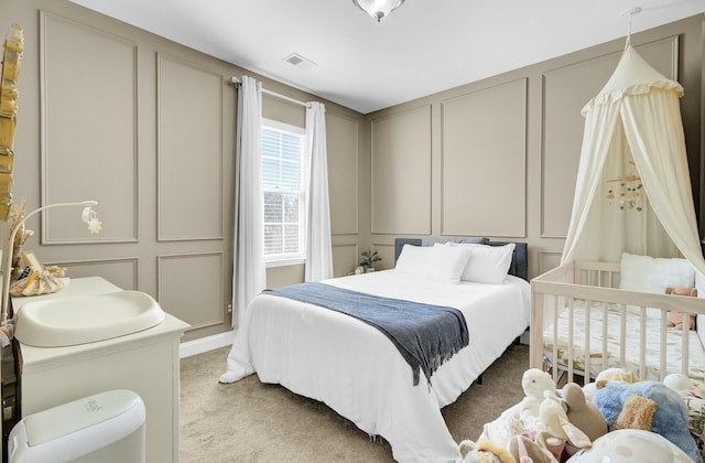 bedroom featuring visible vents, a decorative wall, and light colored carpet