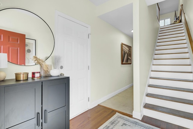 entryway featuring baseboards, stairway, and wood finished floors