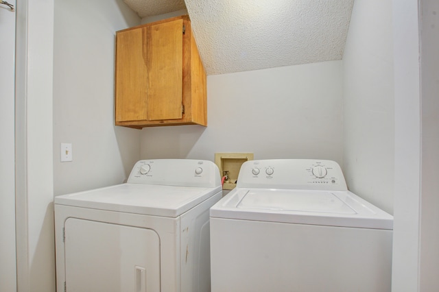 laundry room with washing machine and dryer, cabinets, and a textured ceiling