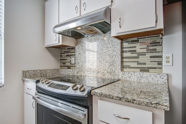 kitchen with decorative backsplash, light stone countertops, electric stove, and white cabinetry