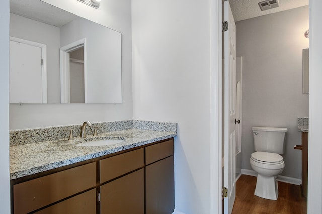 bathroom featuring vanity, a textured ceiling, toilet, and wood-type flooring