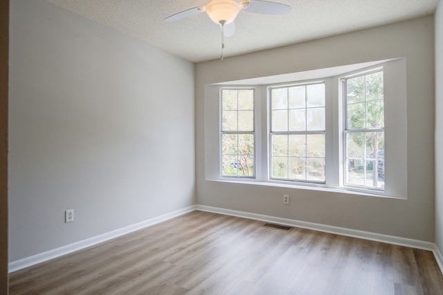 unfurnished room with ceiling fan, a textured ceiling, light hardwood / wood-style floors, and a wealth of natural light