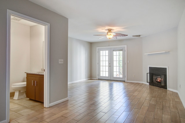 unfurnished living room with ceiling fan, french doors, and light hardwood / wood-style flooring