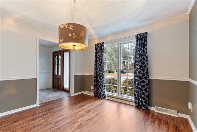 unfurnished room with hardwood / wood-style flooring, crown molding, and a textured ceiling